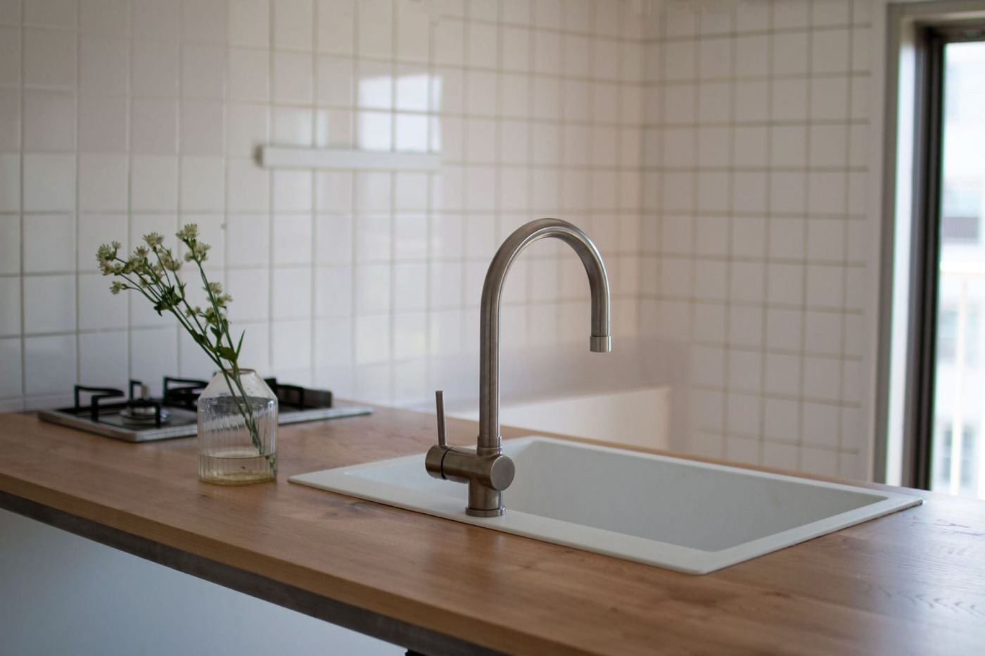 『クォーツシンク』と合わせて造作した、木天板のキッチン。つくりながら、みんなが集まり食べる、そんな過ごし方を叶えてくれる（カスタム ナラ（節・白太有）／角丸2mmR・面取り2mmR・T25・セラウッド塗装）
