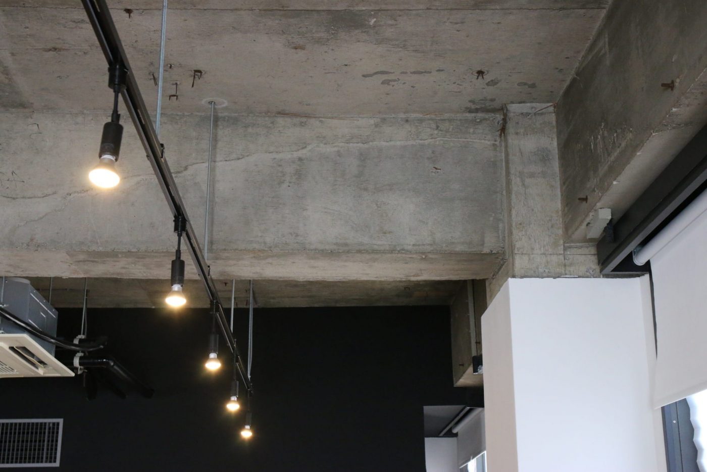 コンクリートの躯体を現しにした天井。照明は既存の蛍光灯を撤去し、配線ダクトレールを設置。