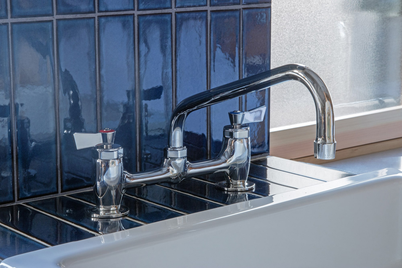 どこかクラシカルな風貌は、ツヤがあるタイルや陶器製シンクとも好相性。（台付けツインレバー混合栓 L200）
