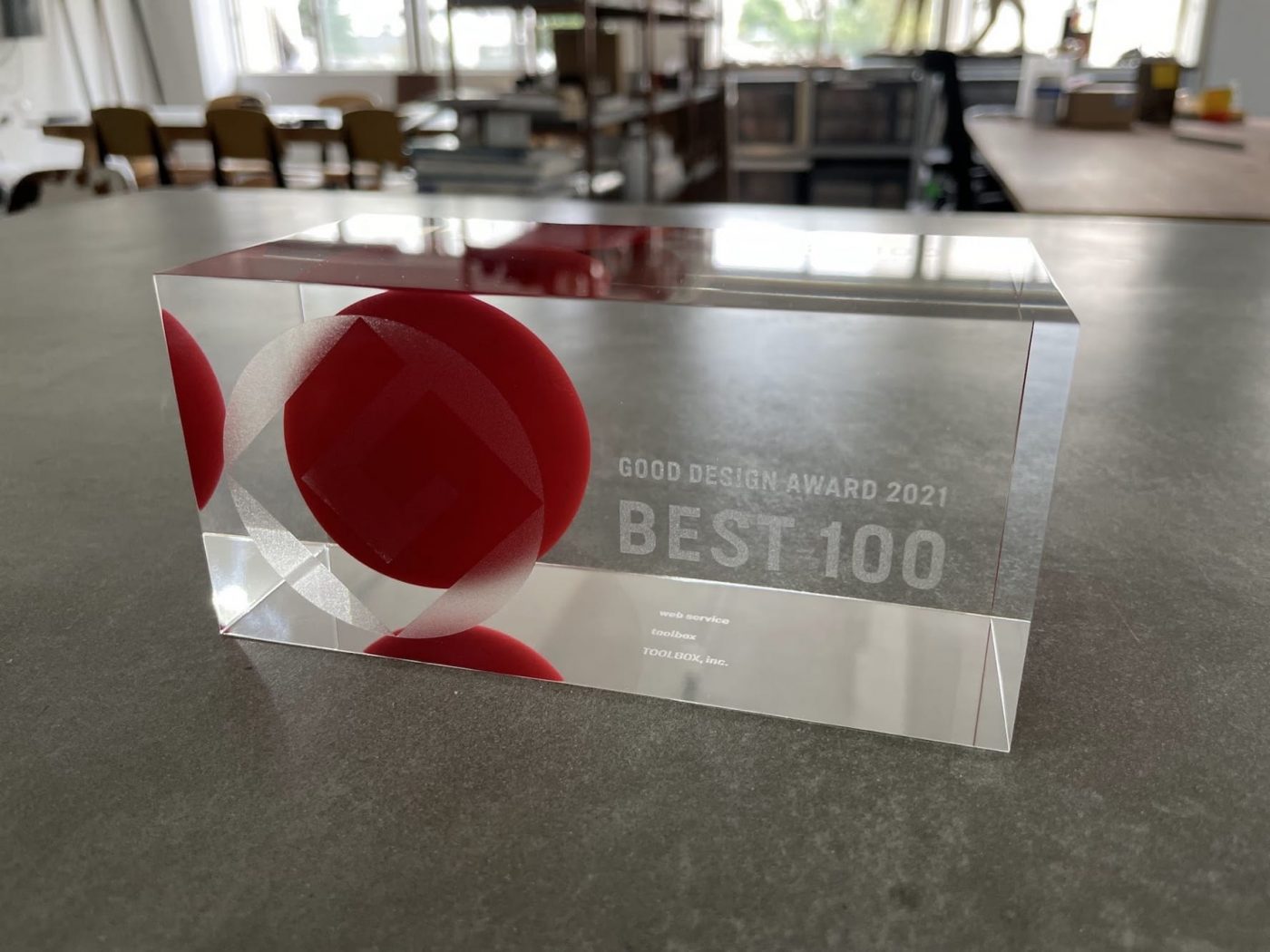 BEST100受賞のトロフィー。見る角度によって中の赤い丸が球体に見えるグッドデザイン。