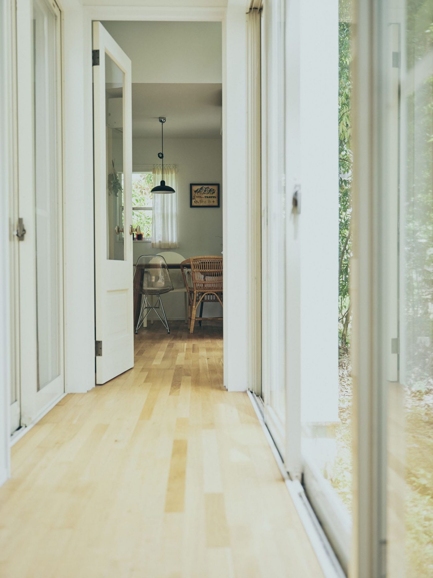 玄関からリビング側を見た長め。『木製パインドア』は白く塗装。右手には中庭が広がります。（撮影：Masanori Kaneshita ）