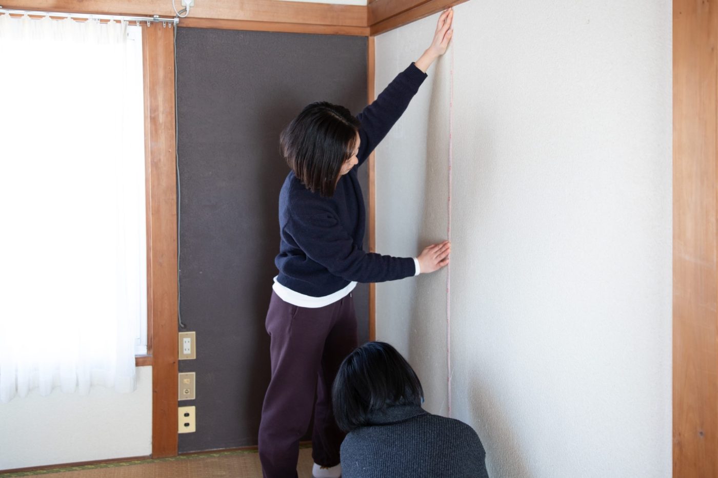 2人がかりでしっかりはじとはじに合わせて測ります。壁紙の継ぎ目に合わせて垂直になるように。