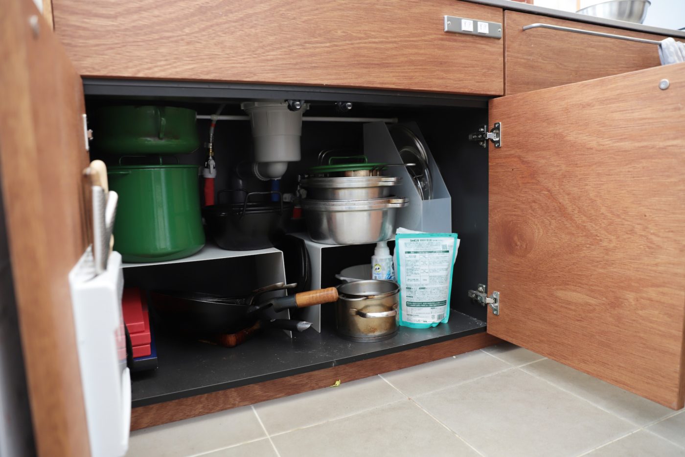 木製システムキッチンのシンク下スペースはMUJIの収納アイテムを取り入れて工夫しています。