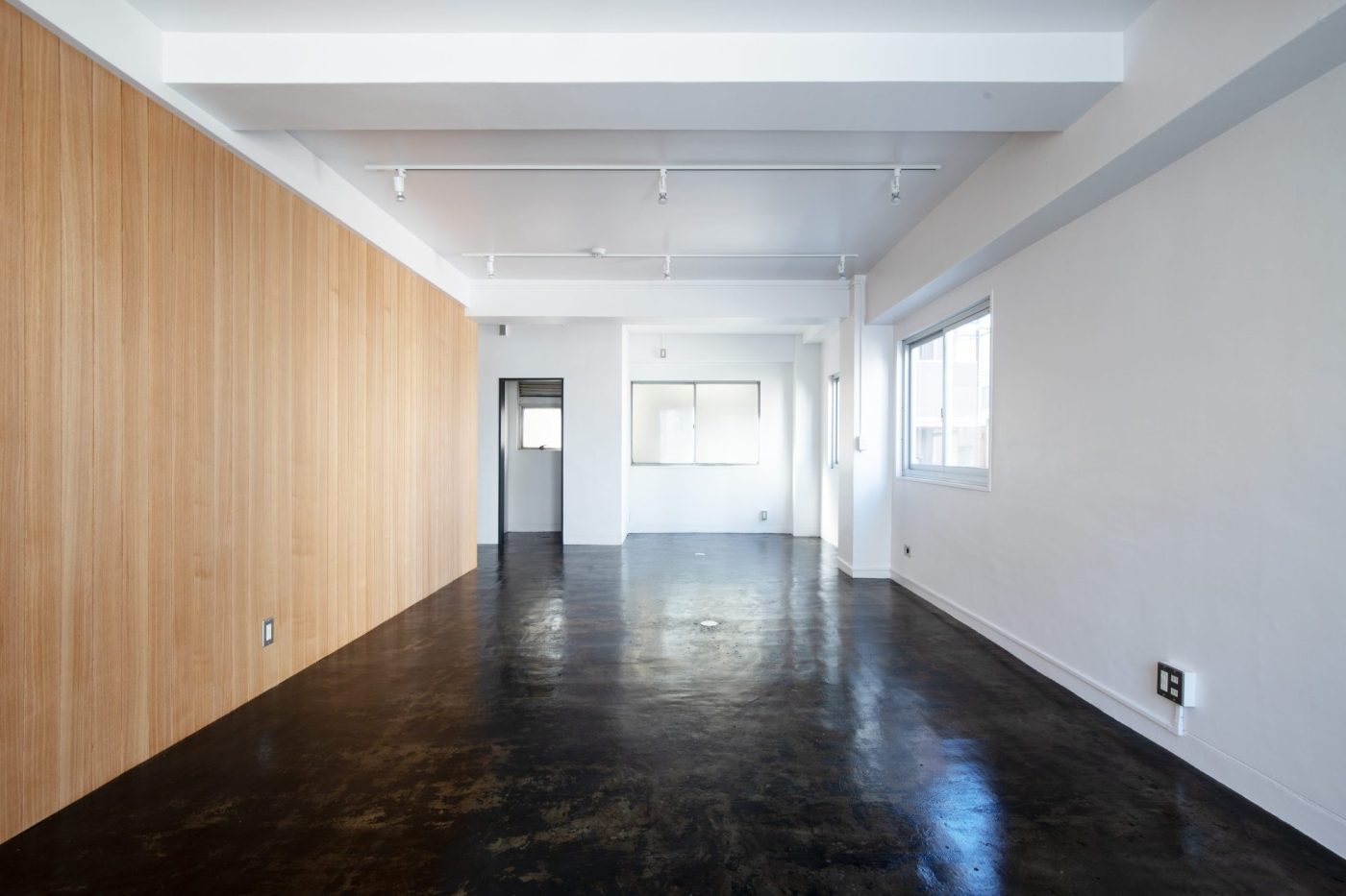 白塗装の壁面とモルタル床のコントラストに、「ウッドウォールパネル」が映えるオフィス空間。