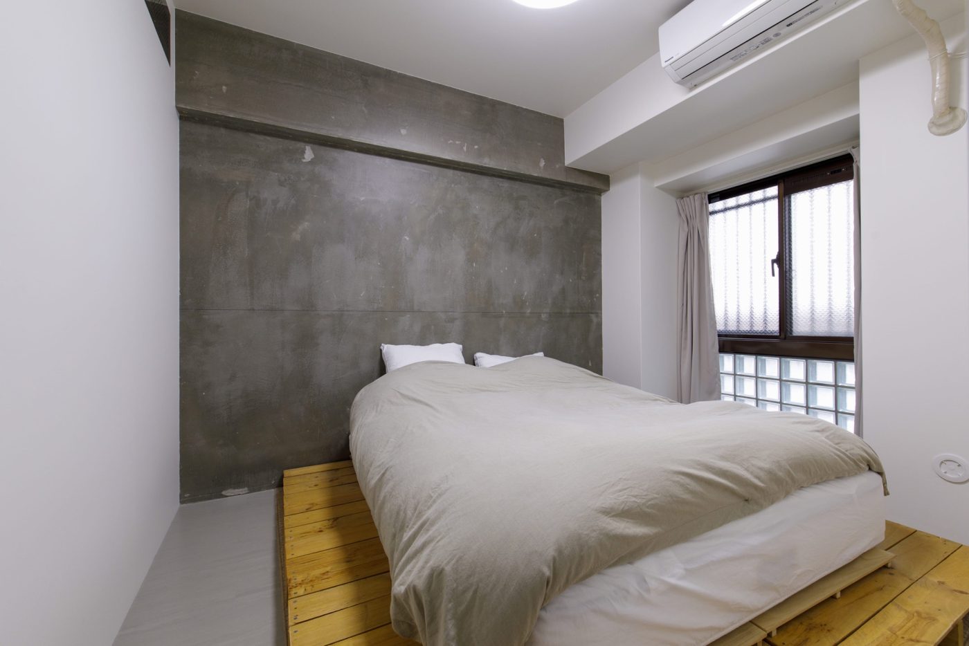 ベッドルームも、コンクリート躯体現しと木製パレットでざっくりとした素材感の空間に。（撮影：マツダナオキ）