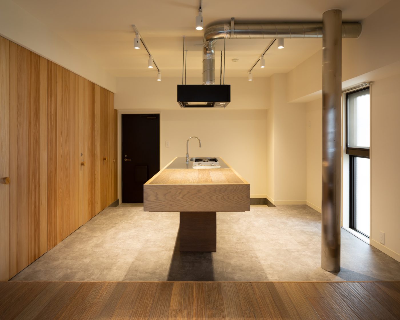 扉を開けた途端、広がる印象的なキッチンスペース。床を異素材にすることで、壁やキッチンの木の素材感が際立っています。