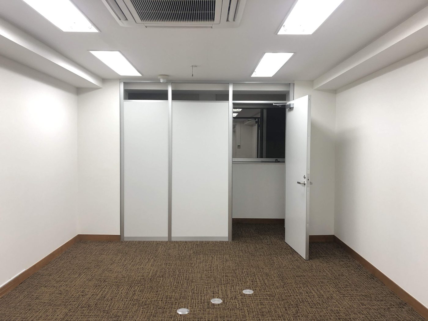 Before：タイルカーペットが敷かれて、アルミパーティションで間仕切られた既存のオフィス。