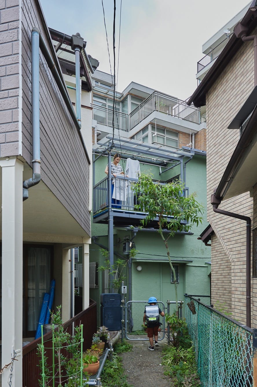 鉢植えの並んだ路地と、裏手には新しいマンション……新旧入り混じりな感じが不思議な光景。この小道も含め、笹本さん一家の敷地です。（撮影：Masanori Kaneshita）