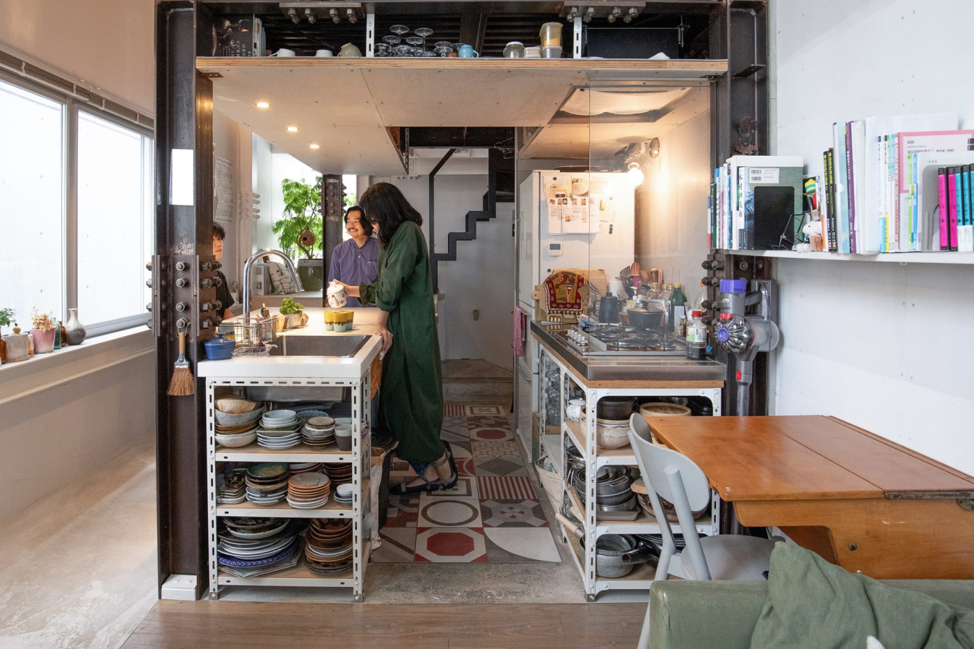 部屋の中央に位置するキッチン兼ダイニング。床はモルタルに中央だけカラフルなタイルで華やかさをプラス。