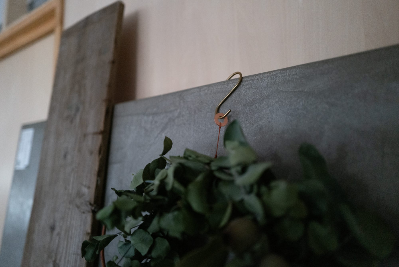 壁に固定せず、立て掛けた板に真鍮のS字フックで引っ掛けて。リースに付いてくる銅のワッシャーがチャームポイント。