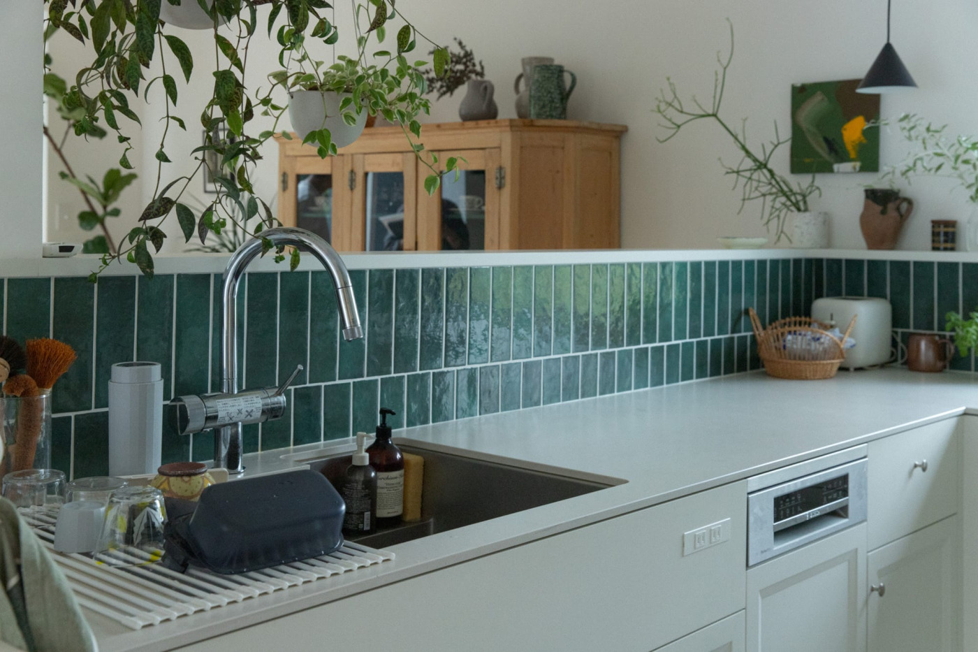 ダイニング側に向かってシンクがある配置。手元が隠れる高さに立ち上げた壁にもグリーンのタイルを貼って。