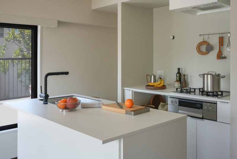 II型キッチンの​天板に​使用した​事例。整然とした​雰囲気の​漂う​キッチンに、​天板の​やわらかな​白と、​果物のは​っきりと​した​カラーの​コントラストが​気持ちいい。​（見付20 オフホワイト + スクエア520シンク）​
