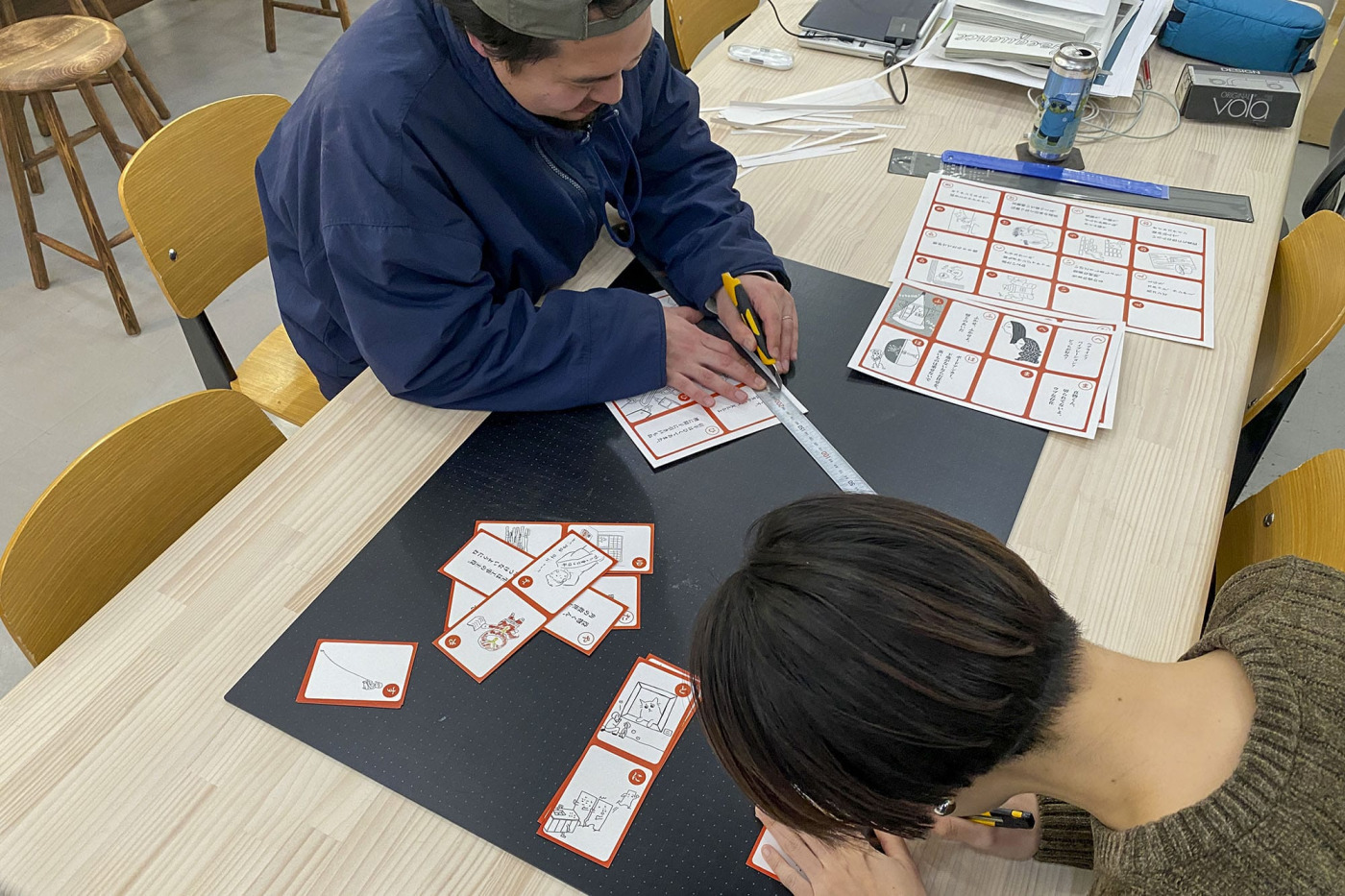 「#19 建築現場用語カルタをつくろう！」の回で盛り上がった内容が本当にカルタに！嬉々としてカットするTBK（ツーボックス工事班）のメンバー。