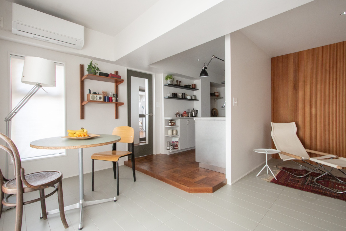 廊下から緩やかにキッチンに繋がる動線。グレー、白、木の色がバランスよくまとまった空間に、黒い小物でメリハリを付けています。