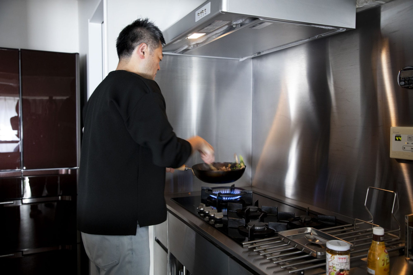 ハイパワーのコンロで中華鍋を振るい炒め物。壁はキッチンと同素材のステンレス仕上げで掃除しやすい。
