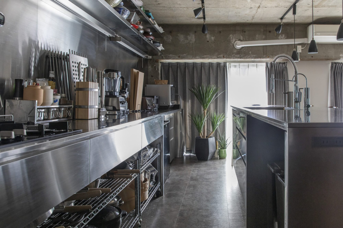 壁際はコンロ下にオープン可動式の収納を。奥にはワインセラーも。アイランド下は、ごみ箱とシンク奥に食洗機。