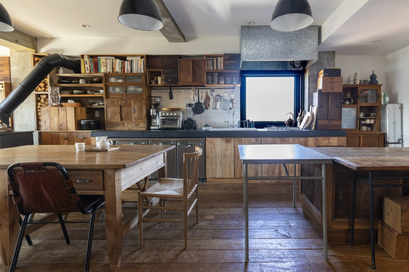 日本の古い棚や木箱を壁面に打ち付けたブリコラージュキッチン。窓に合わせてブリキの換気扇カバーを造作。（事例協力：CIRCUS inc.）