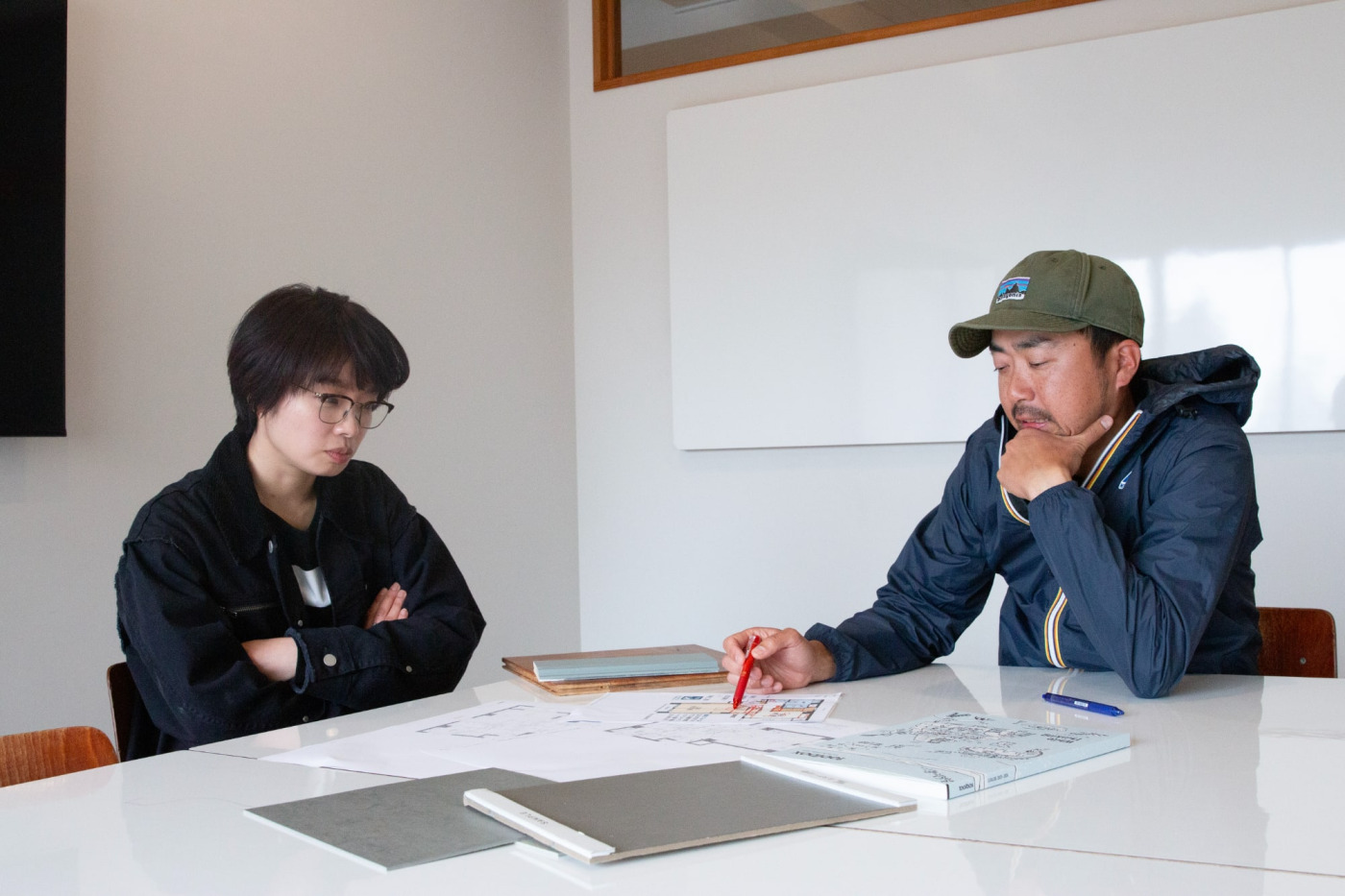 物件の間取り図や商品サンプルを並べて、真剣に話し込む山下（左）と一杉。