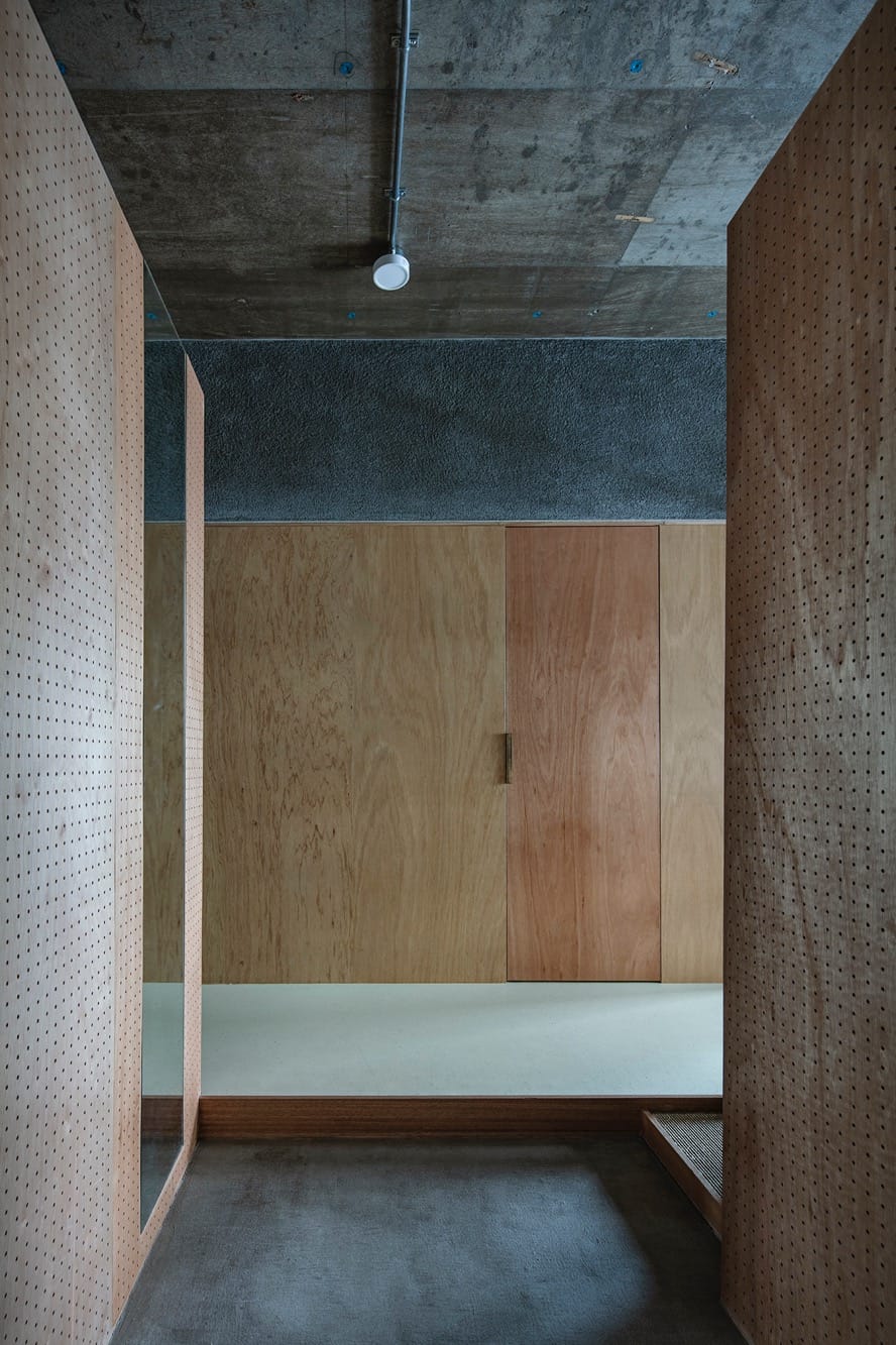 廊下の中腹、玄関からの景色。壁の仕上げのようにフラットに仕込まれた姿見が、空間に奥行きと機能を与えています。