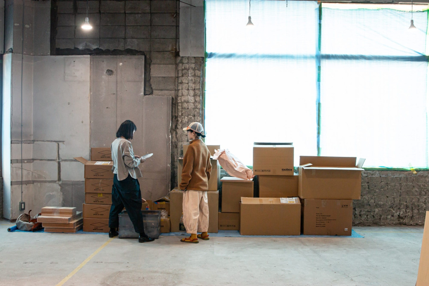 什器が組み上がる横で、届いた商品の検品に追われるMDスタッフ大迫。梱包や陳列の計画も山場を迎えています。