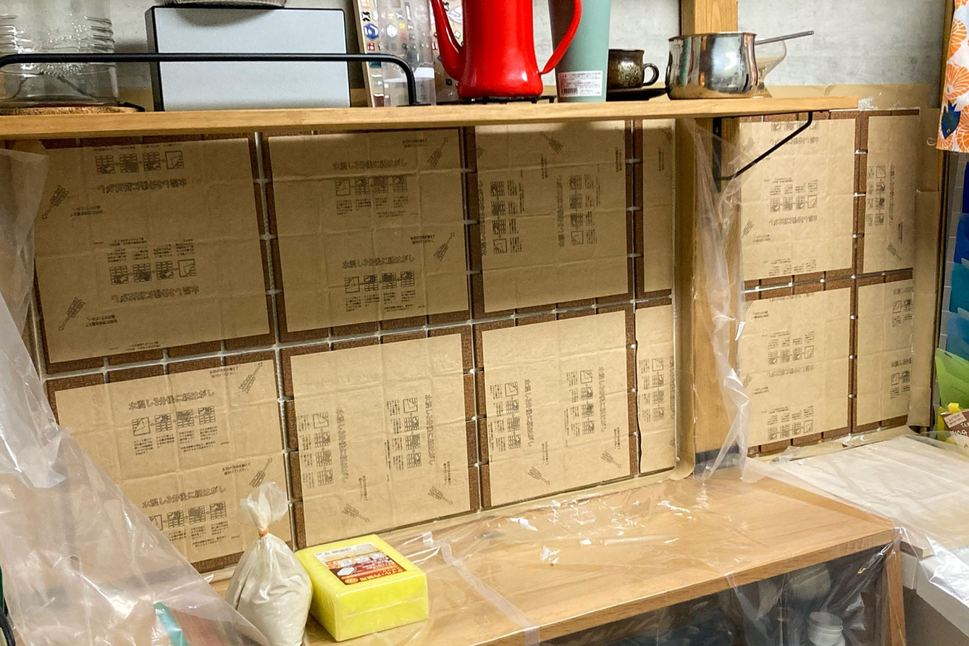 シート状のまま、壁にタイルを貼り付けて、ボンドが乾くまで1日待ちます。養生シートはわざわざ買わず、90Lのゴミ袋を割いて利用したそう。