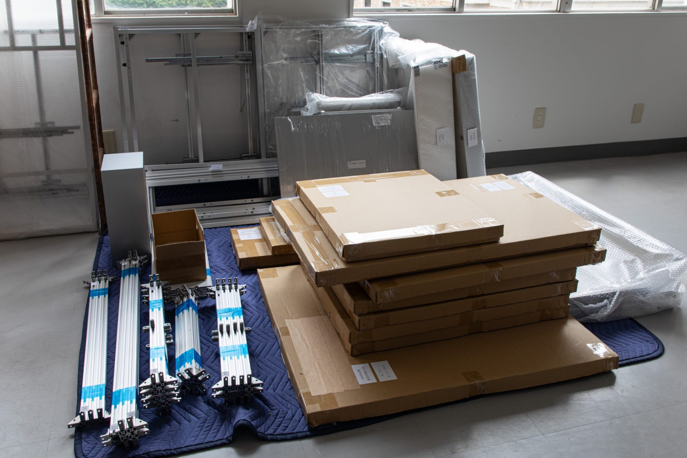 荷解きと中身のチェックが終わった状態。扉などの面材は傷が付かないよう、段ボールに入れた上で重ねてあります。沢山のパーツが一斉に届くため、予め種類ごとに分けて整理しておけると、この後の組み立てがよりスムーズになりそうです。
